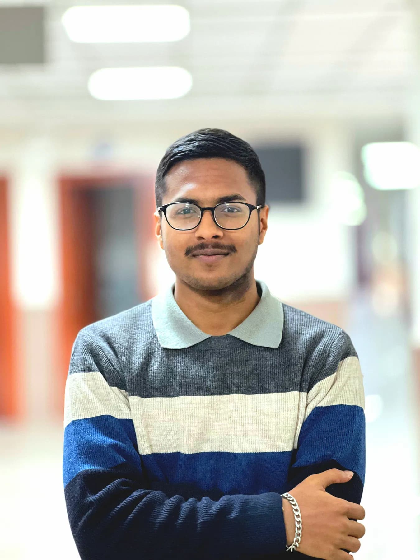Gantavya Bansal, smiling, arms folded, in a striped sweater